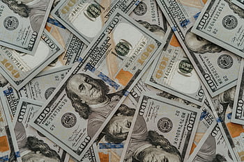 Close-up of American 100 dollar bills scattered, highlighting wealth and currency concepts. HD wallpaper