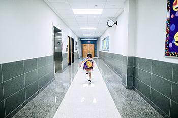 A child runs through a bright school hallway, emphasizing modern architecture and energy. HD wallpaper