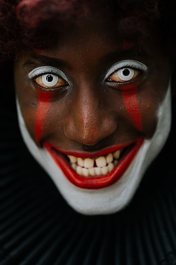 Close-up of a person in eerie clown makeup with a haunting smile and intense eyes. HD phone wallpaper
