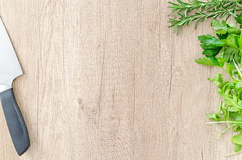 Top view of fresh rosemary and parsley with a chef's knife on a wooden surface, offering ample copyspace. HD wallpaper