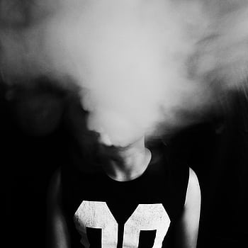 A dramatic black and white of a person obscured by smoke, creating a mysterious effect. HD phone wallpaper