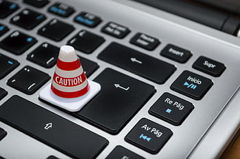 Miniature caution cone on a computer keyboard symbolizing data security and control. HD wallpaper