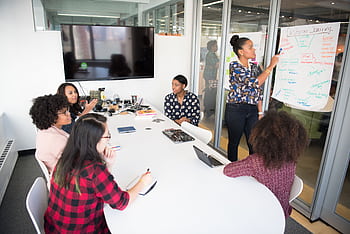 A multicultural office team engages in a collaborative brainstorming session around a conference table. HD wallpaper