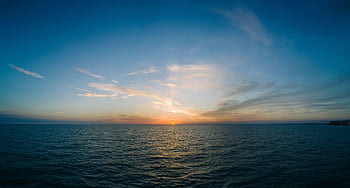Peaceful ocean sunset with vibrant sky and calm waters, ideal for tranquil scenes. HD wallpaper