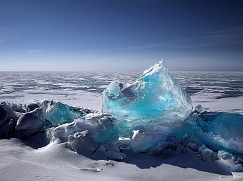 Captivating ice formation on a frozen lake under a bright blue sky during winter. HD wallpaper