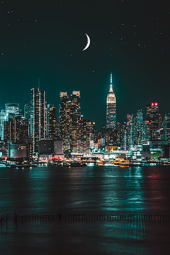Captivating nighttime view of New York City skyline with illuminated skyscrapers and moon. HD phone wallpaper