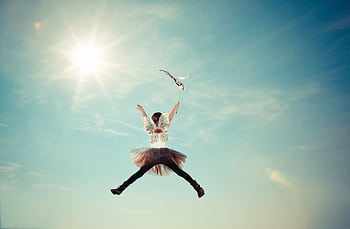 A young girl joyfully leaps in a fairy costume under the bright sun, capturing a moment of dom and whimsy. HD wallpaper