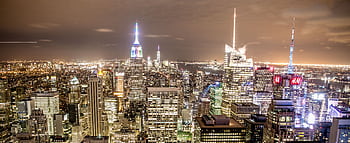 Elevated view of New York City skyline with illuminated skyscrapers and Empire State Building at night. HD wallpaper
