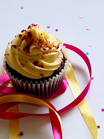 Tempting chocolate cupcake with creamy icing, adorned with colorful ribbons and confetti for a festive celebration. HD phone wallpaper