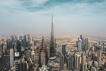 A breathtaking aerial view of Dubai's skyline featuring Burj Khalifa amidst modern skyscrapers under a clear sky. HD wallpaper