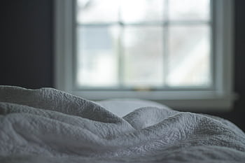 A tranquil bedroom view with a quilted blanket by the window softly lit by morning light, ideal for relaxation themes. HD wallpaper
