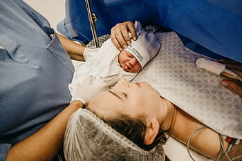 A mother cradling her newborn immediately after childbirth in a hospital setting. HD wallpaper
