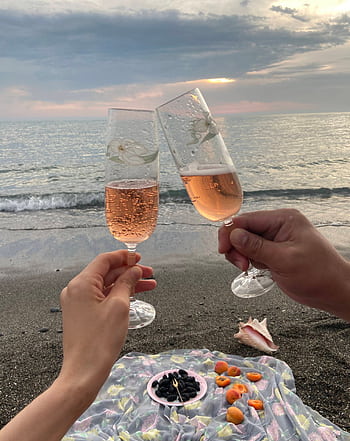 Couple toasting on a tranquil beach with champagne glasses, capturing a moment of romance at sunset. HD phone wallpaper