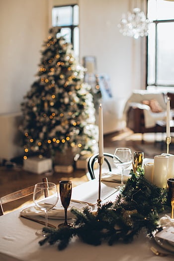 Warm and luxurious Christmas table setting with candles and a decorated tree in the background. HD phone wallpaper