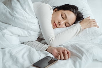 A serene of a young woman sleeping with a smart nearby, capturing a moment of calmness and relaxation. HD wallpaper