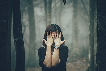 Mystical portrait of a woman covering her face in a foggy forest setting. HD wallpaper