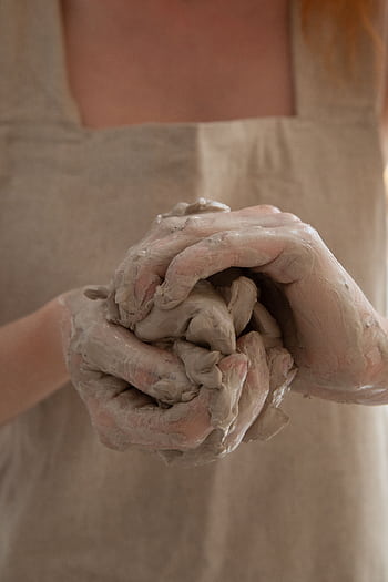 Close-up of hands molding clay in a pottery studio, showcasing artisan craftwork. HD phone wallpaper
