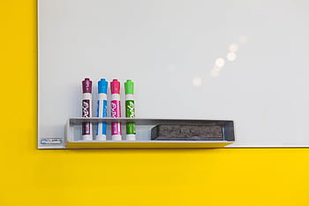 Colorful markers and eraser on a bright whiteboard in an office setting, ideal for brainstorming and planning. HD wallpaper