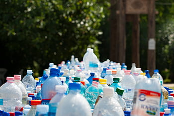 A vibrant collection of plastic bottles in an outdoor recycling setup, showcasing environmental awareness. HD wallpaper