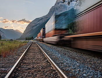 Vivid of a freight train on tracks beneath majestic mountains in Field, BC. HD wallpaper
