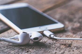 A close-up of a smart and ears lying on a wooden surface, capturing a moment of connectivity and technology. HD wallpaper