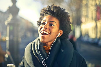 Smiling young woman enjoying music in urban Budapest setting. Vibrant and joyful moment. HD wallpaper