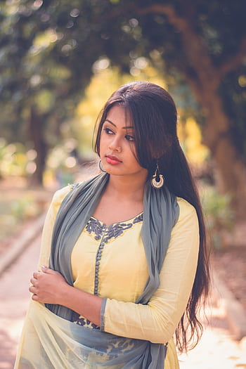 Portrait of an elegant South Asian woman in a stylish yellow dress and scarf, captured outdoors in natural light. HD phone wallpaper