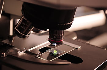 Detailed view of a microscope with a slide in a laboratory environment. HD wallpaper