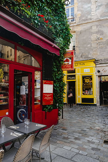 Explore a que Parisian café scene with vibrant colors and ivy-covered walls on a bustling street. HD phone wallpaper