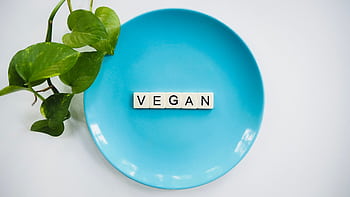 A blue plate with the word 'VEGAN' and a leafy plant, symbolizing a plant-based diet. HD wallpaper