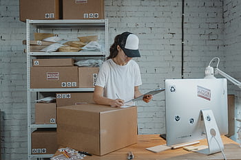 Woman managing shipping logistics for her small business, ensuring accurate inventory and order fulfillment. HD wallpaper