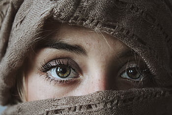 Intense eyes of a woman wrapped in a knitted scarf, showcasing winter fashion. HD wallpaper