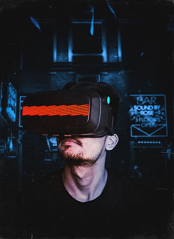 Young man immersed in a virtual reality experience using a VR headset, showcasing futuristic tech in a gaming environment. HD phone wallpaper