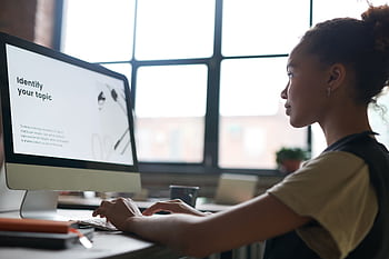 A woman attentively working on a computer in an office setting, focused on a presentation screen. HD wallpaper