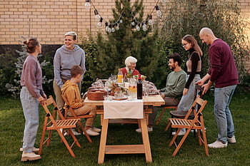 A cheerful family gathering outdoors with food and drinks on a summer day. HD wallpaper