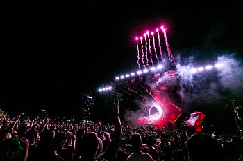 A vibrant nighttime festival with fireworks, showcasing a lively crowd and performance stage. HD wallpaper