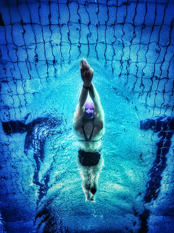 Captivating underwater shot of a swimmer in a pool with clear blue water. HD phone wallpaper