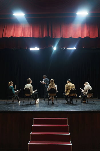 A group of actors rehearsing on stage under spotlights, creating an immersive theater experience. HD phone wallpaper