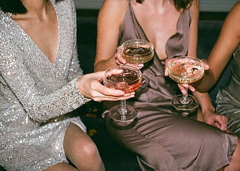 Three women in stylish dresses toasting with champagne at a festive gathering. HD wallpaper