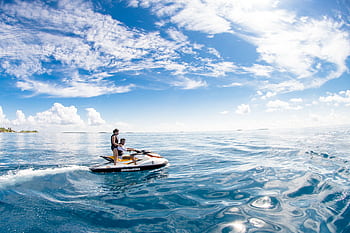 Enjoy a thrilling jet ski ride in the serene waters of Kaafu Atoll, Maldives. HD wallpaper