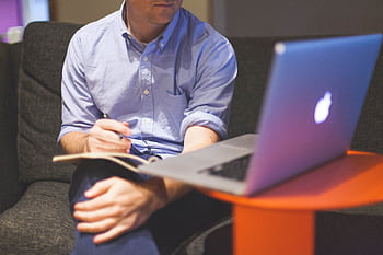 Man working remotely with laptop and notebook, noting ideas. HD wallpaper