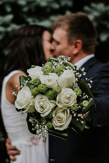 A couple embracing with a focus on a white rose and green floral wedding bouquet. HD phone wallpaper