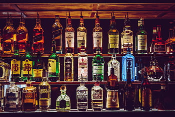 An array of various liquor bottles beautifully displayed on a bar shelf. HD wallpaper