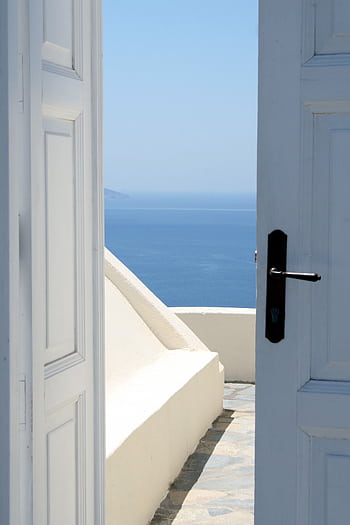 A serene view of the blue sea through an open doorway, capturing Santorini's iconic architecture. HD phone wallpaper