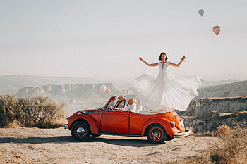 Bride and groom celebrating their wedding atop a vintage car in Cappadocia, Turkey. HD wallpaper