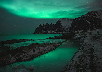 Stunning view of the aurora borealis illuminating a snowy mountain range at night. HD wallpaper