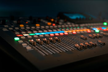 Close-up of a professional sound mixer with colorful glowing controls in a dimly lit studio. HD wallpaper