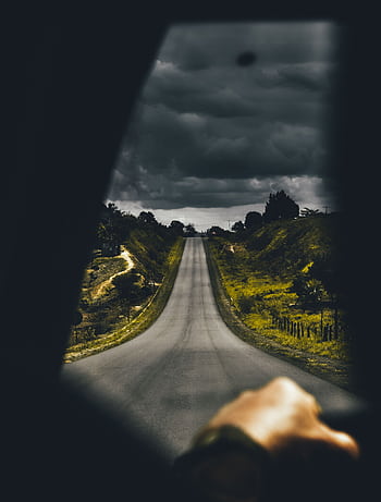 A moody drive on an open road with dark clouds overhead, capturing a sense of adventure and solitude. HD phone wallpaper