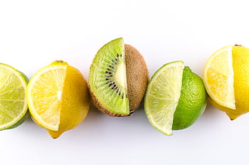 Colorful arrangement of kiwi, lemon, and lime slices showcasing freshness and vibrancy on a white background. HD wallpaper
