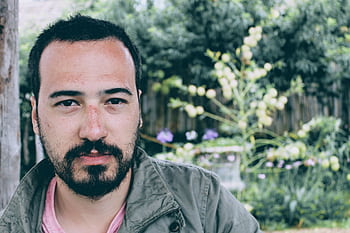 Portrait of a young man with facial hair, outdoors in a natural setting. Serious expression. HD wallpaper